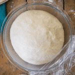 Pizzateig Rezept – aufgegangener Pizzateig in einer Glasschüssel mit Frischhaltefolie